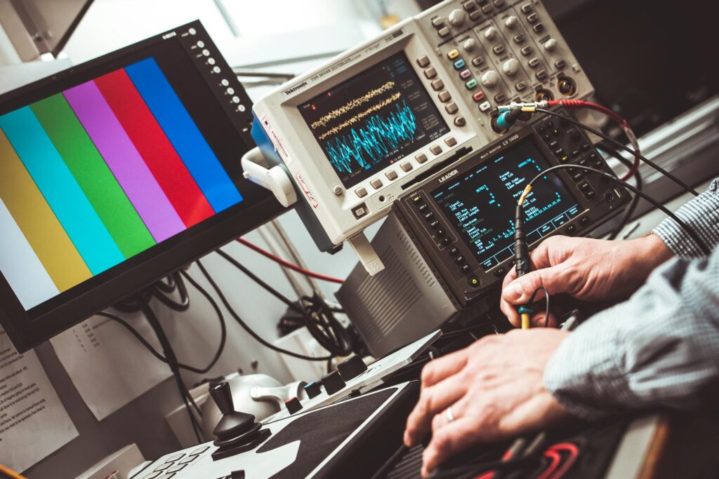 Technician operating laboratory electronic testing and measurement devices with colorful display.